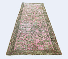 A vintage Persian runner rug featuring a faded pink field with intricate grey floral patterns.