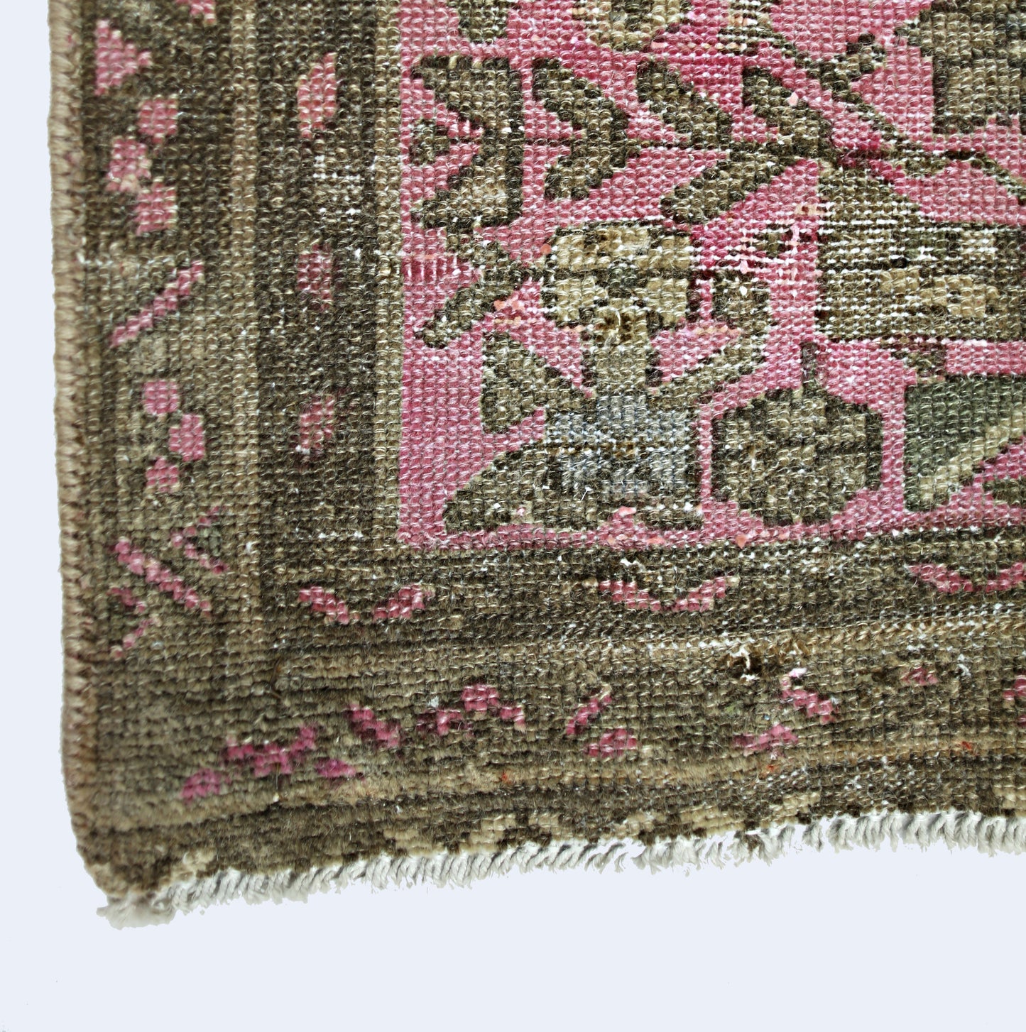 A close-up of a vintage Persian runner featuring a pink field with intricate brown floral patterns.