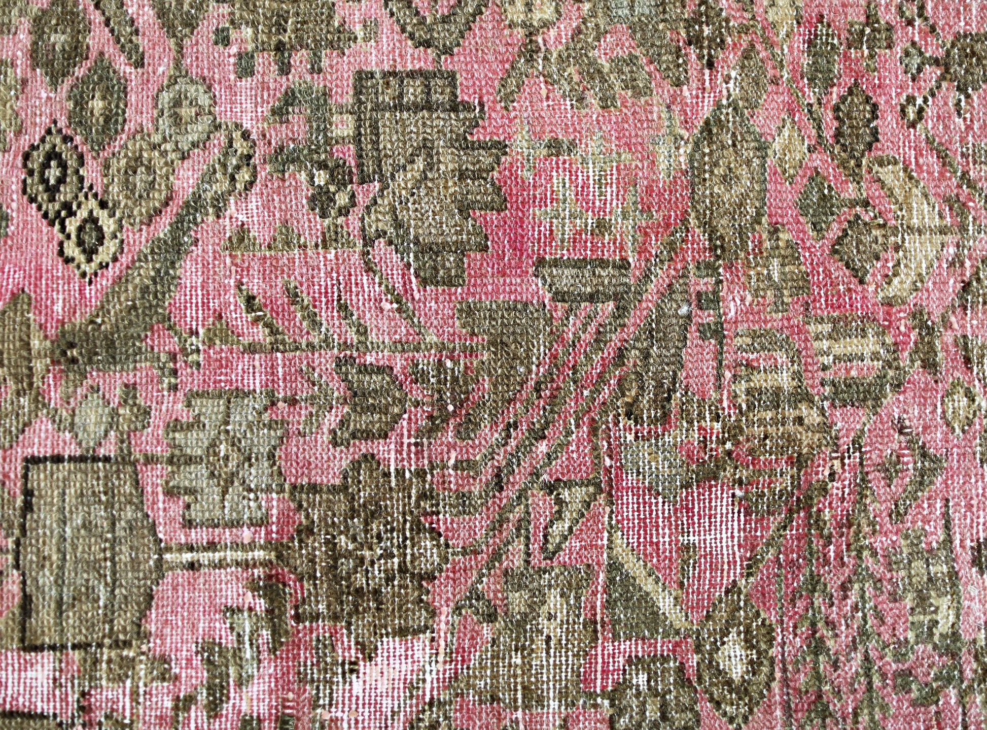 A close-up of a vintage Persian runner featuring intricate floral patterns in olive and pink.