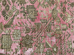 A close-up of a vintage Persian runner featuring intricate floral patterns in olive and pink.