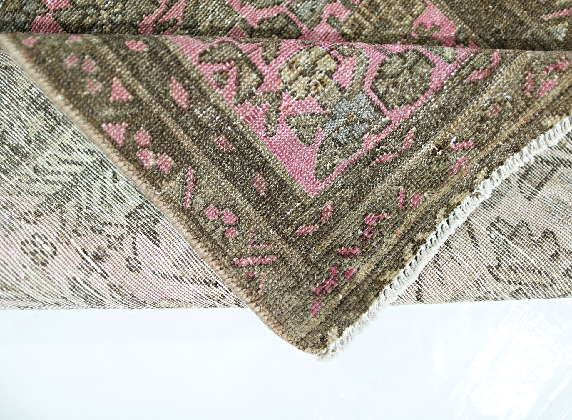 A folded vintage Persian runner featuring a traditional floral pattern in pink and brown tones.