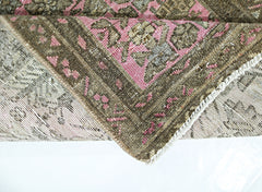 A folded vintage Persian runner featuring a traditional floral pattern in pink and brown tones.