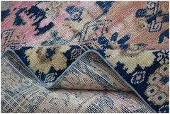 A vintage handwoven Persian runner featuring a faded floral pattern in blue, pink, and beige.