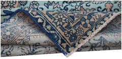 A folded vintage Persian runner featuring intricate blue and beige floral patterns.