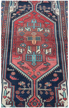 A handwoven vintage Persian runner featuring a geometric red medallion on a dark blue background.
