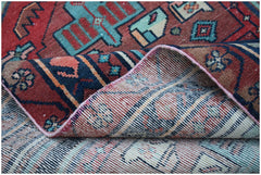 A handwoven vintage Persian runner featuring geometric patterns in red, blue, and cream wool.