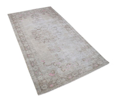 A vintage Persian runner rug featuring a faded beige pattern with subtle pink accents.