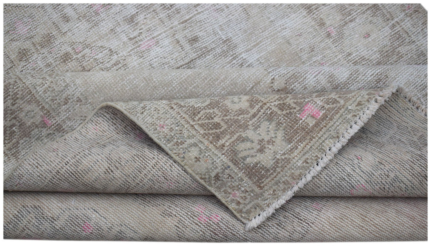 A handwoven vintage Persian runner featuring a faded beige pattern with subtle pink accents.