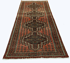 A vintage Persian runner featuring a geometric pattern in shades of red, black, and brown.