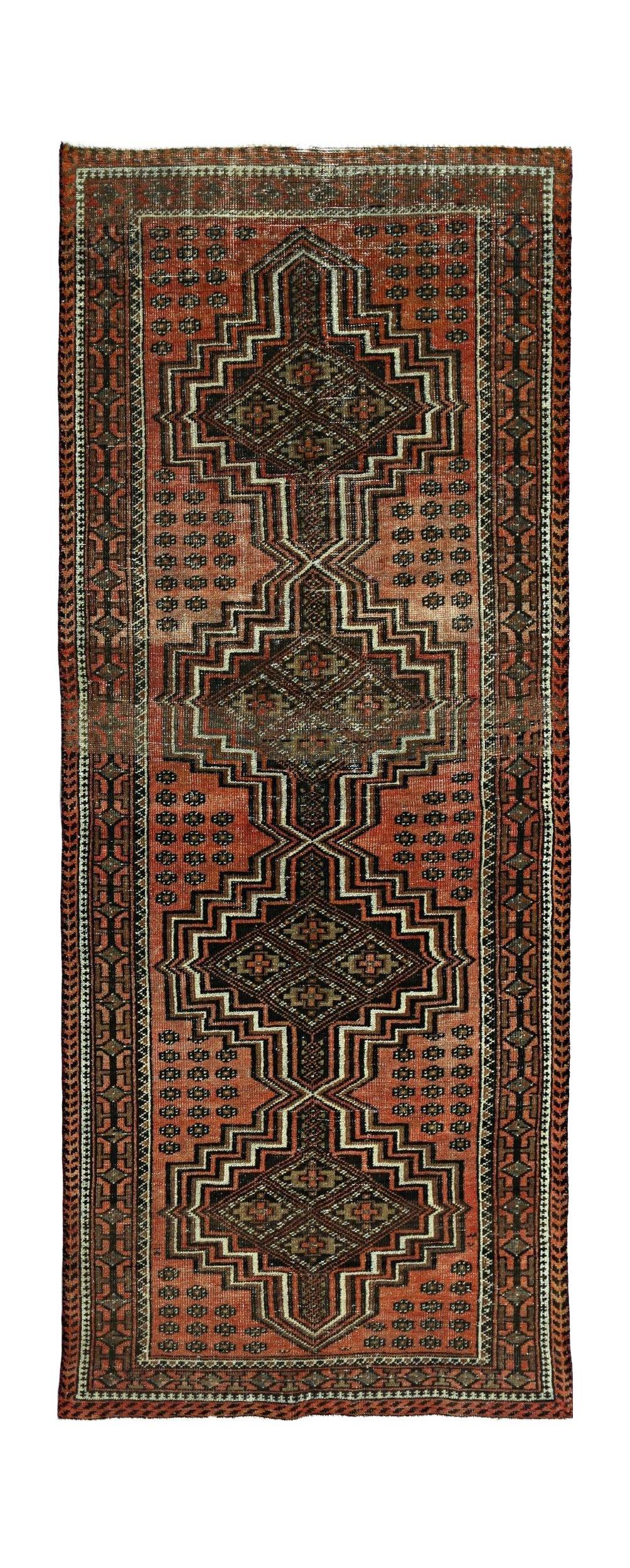 A vintage Persian runner featuring a geometric diamond pattern in shades of red and black.