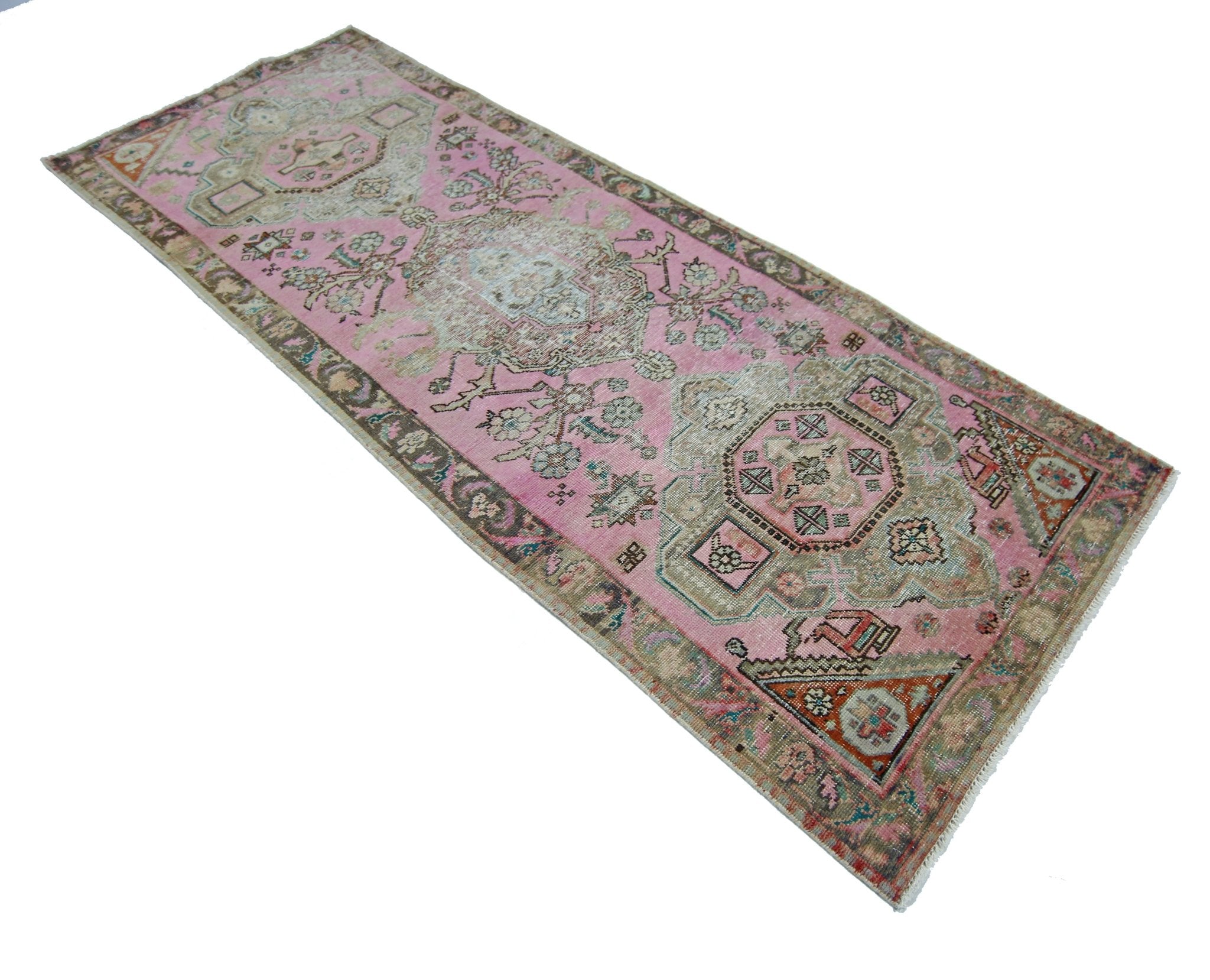A vintage handmade Persian runner rug featuring a pink field with intricate geometric patterns.
