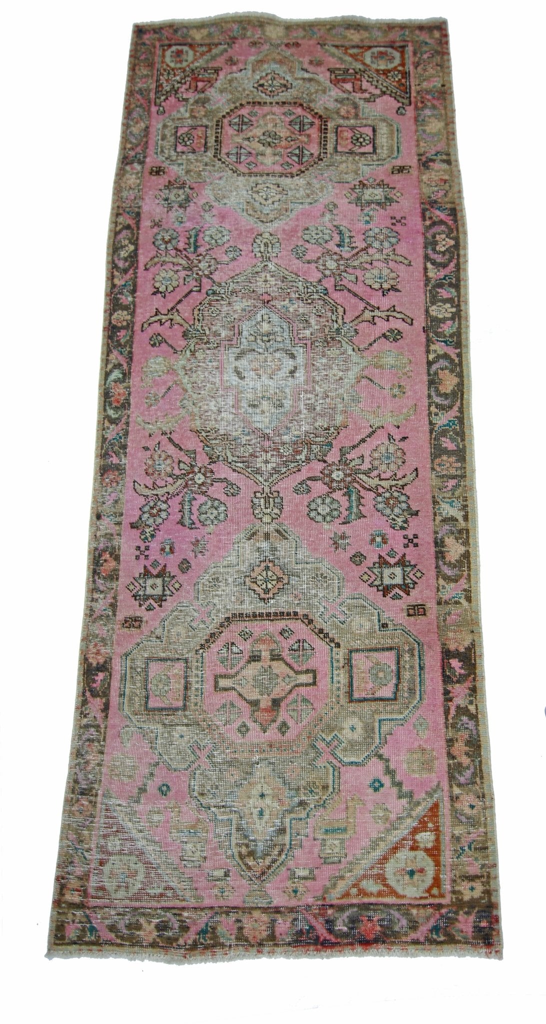 A vintage Persian runner rug featuring a pink field with intricate geometric and floral patterns.