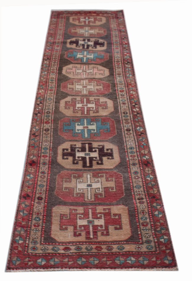 A handwoven vintage Persian runner featuring geometric motifs in red, blue, and brown wool.