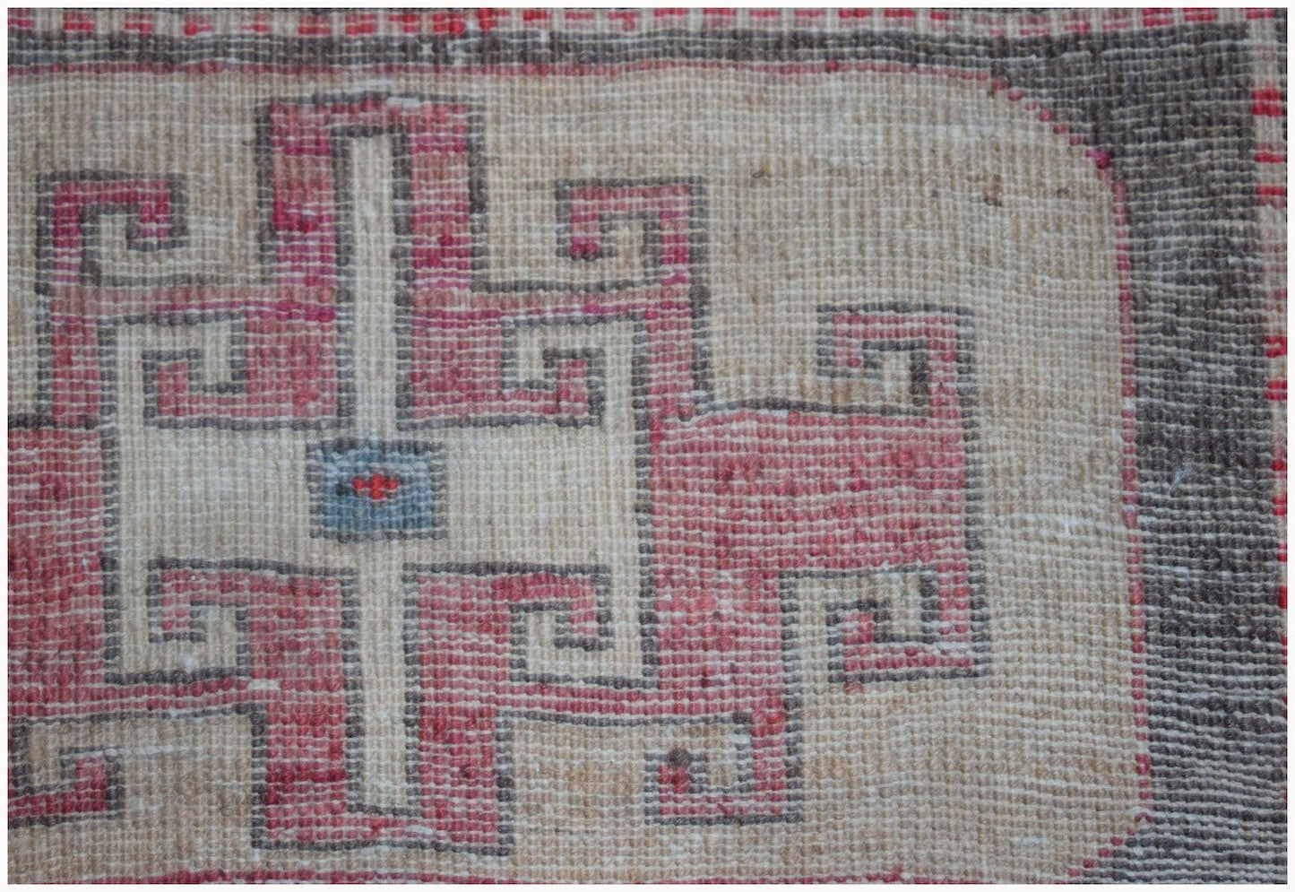 A close-up of a vintage Persian runner featuring a geometric pink and cream patterned design.