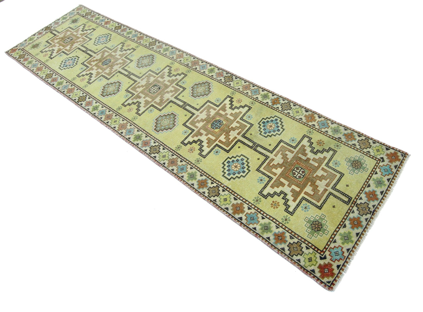 A handmade vintage Persian runner rug featuring geometric patterns in muted tones on a yellow field.
