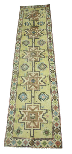 A vintage Persian runner rug featuring geometric patterns in shades of green, brown, and blue.