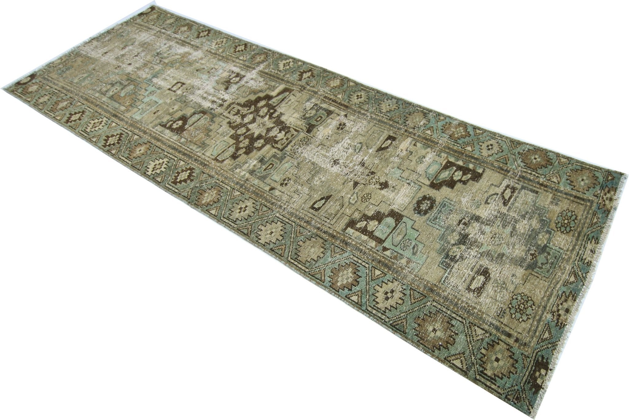A vintage handmade Persian runner rug featuring a distressed geometric pattern in muted earth tones.