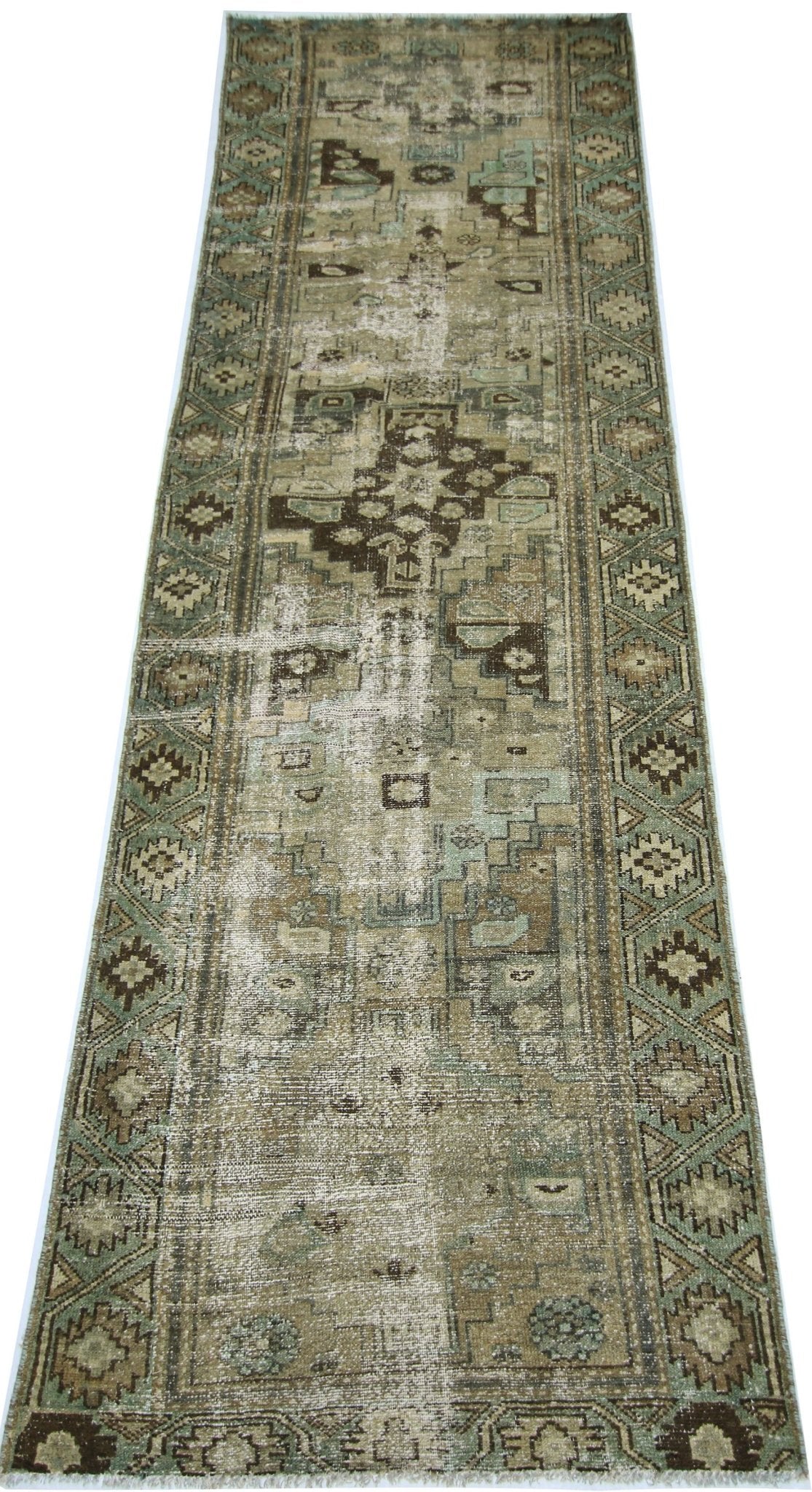 A vintage handmade Persian runner rug featuring a distressed geometric pattern in muted earth tones.