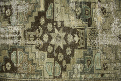 A vintage Persian runner featuring a distressed geometric pattern in shades of brown and sage.