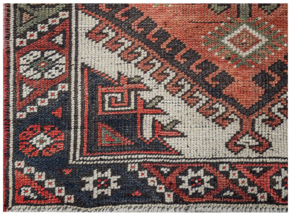 A vintage handwoven Persian runner featuring geometric patterns in red, blue, and cream wool.