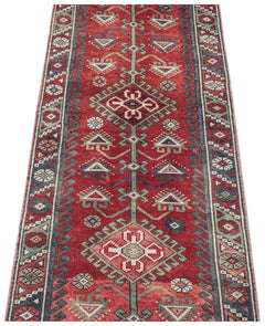 A handwoven vintage Persian runner featuring geometric patterns in red, green, and blue tones.