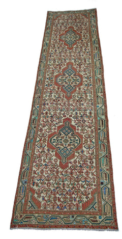 A vintage handmade Persian runner featuring a geometric pattern in red, blue, and cream tones.