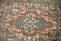 A vintage Persian runner featuring a central geometric medallion in red, blue, and cream tones.