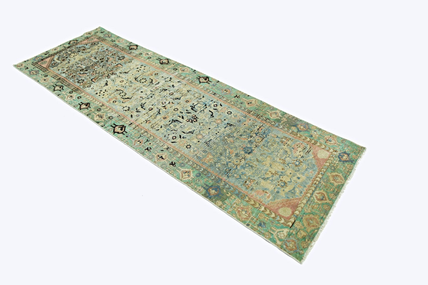A vintage Persian runner rug featuring intricate floral patterns in faded green and blue tones.