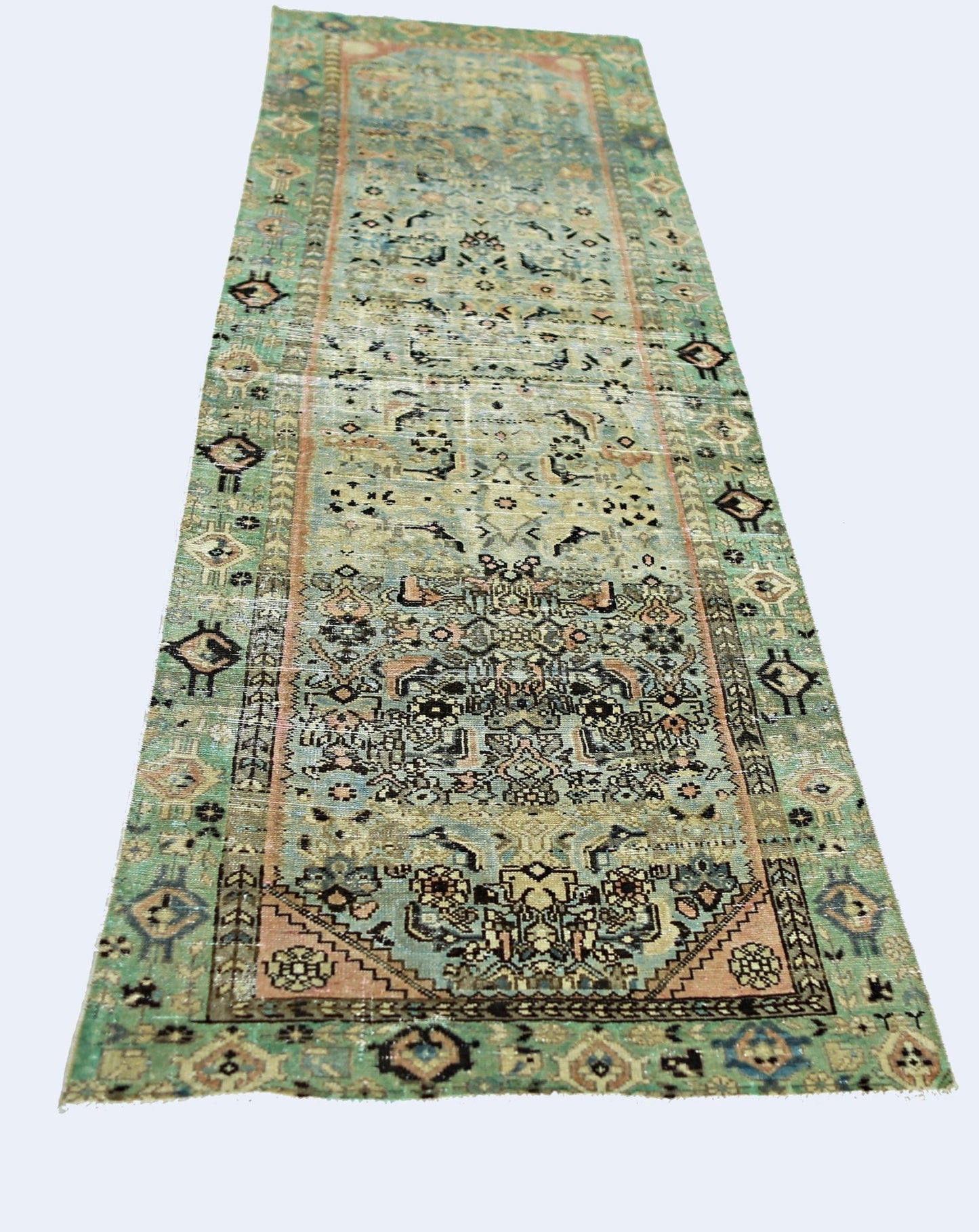 A vintage handmade Persian runner rug featuring intricate floral patterns in faded green and pink.
