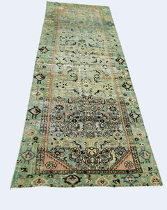 A vintage handmade Persian runner rug featuring intricate floral patterns in faded green and pink.