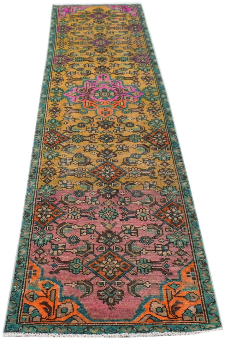 A handmade vintage Persian runner rug featuring a vibrant geometric pattern in gold and pink.