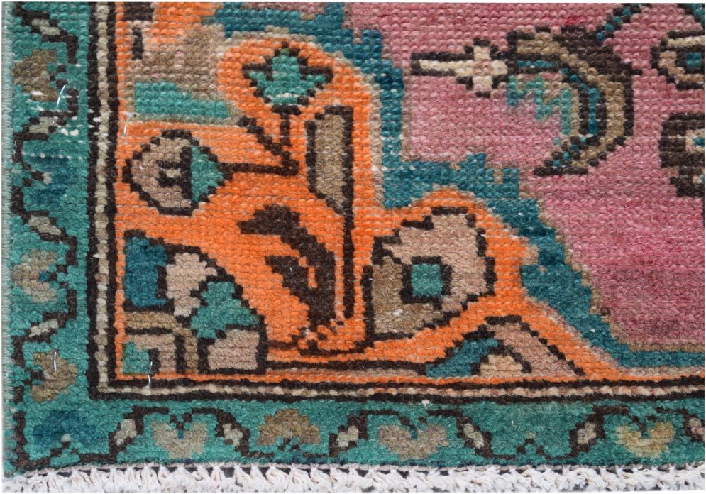 A close-up of a vintage Persian runner featuring a vibrant floral pattern in pink, orange, and teal.