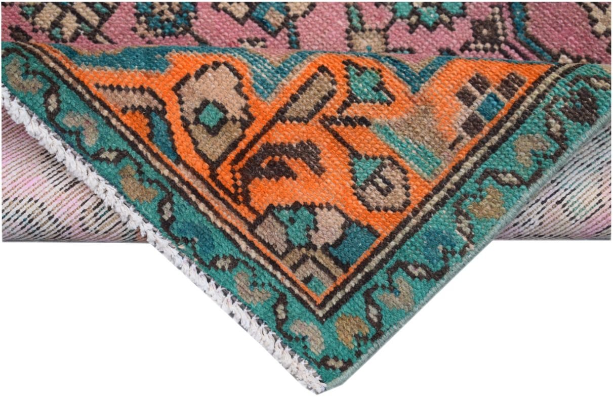 A corner of a vintage Persian runner featuring a vibrant orange, teal, and pink geometric pattern.