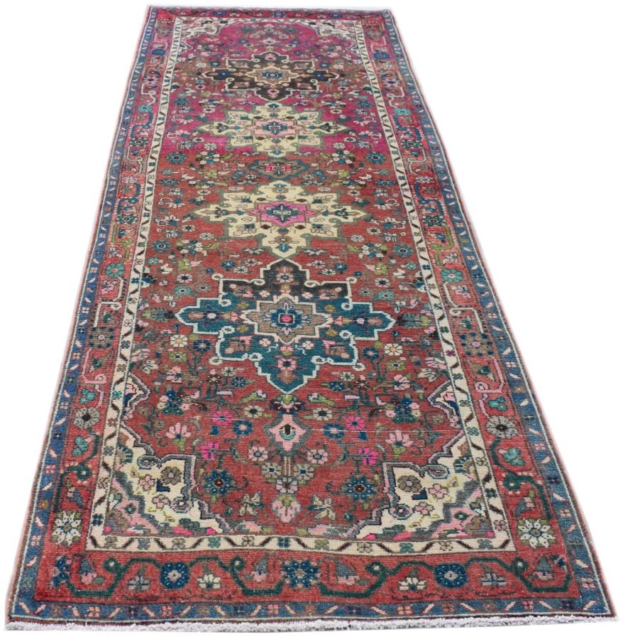 A vintage Persian runner rug featuring a red field with intricate floral patterns and medallions.
