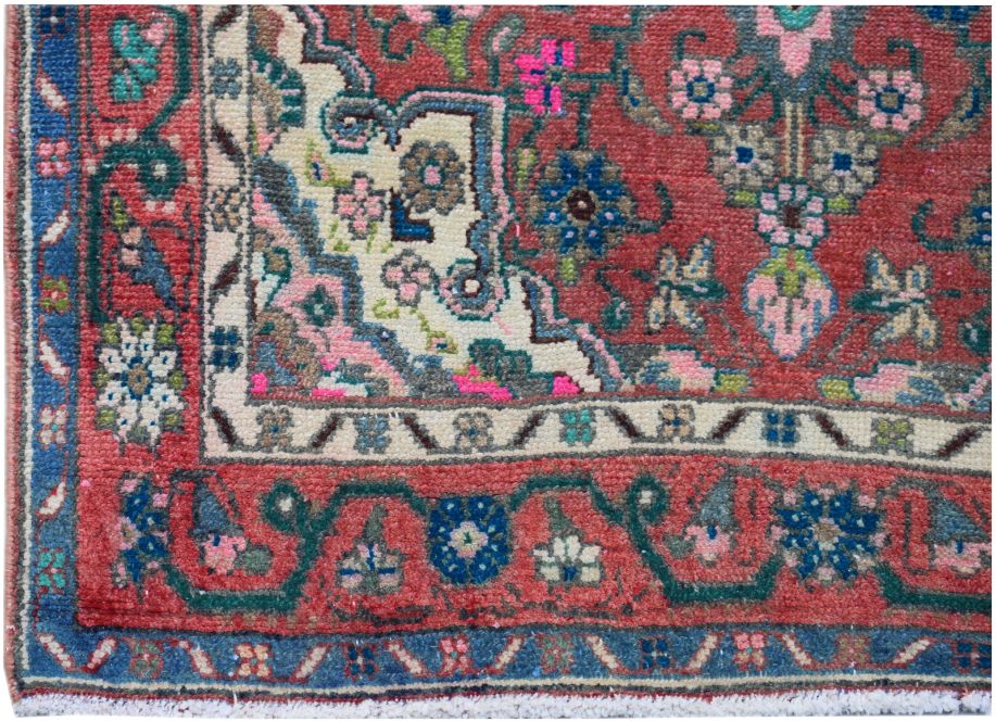 A vintage Persian runner featuring a floral pattern in red, blue, and cream wool.