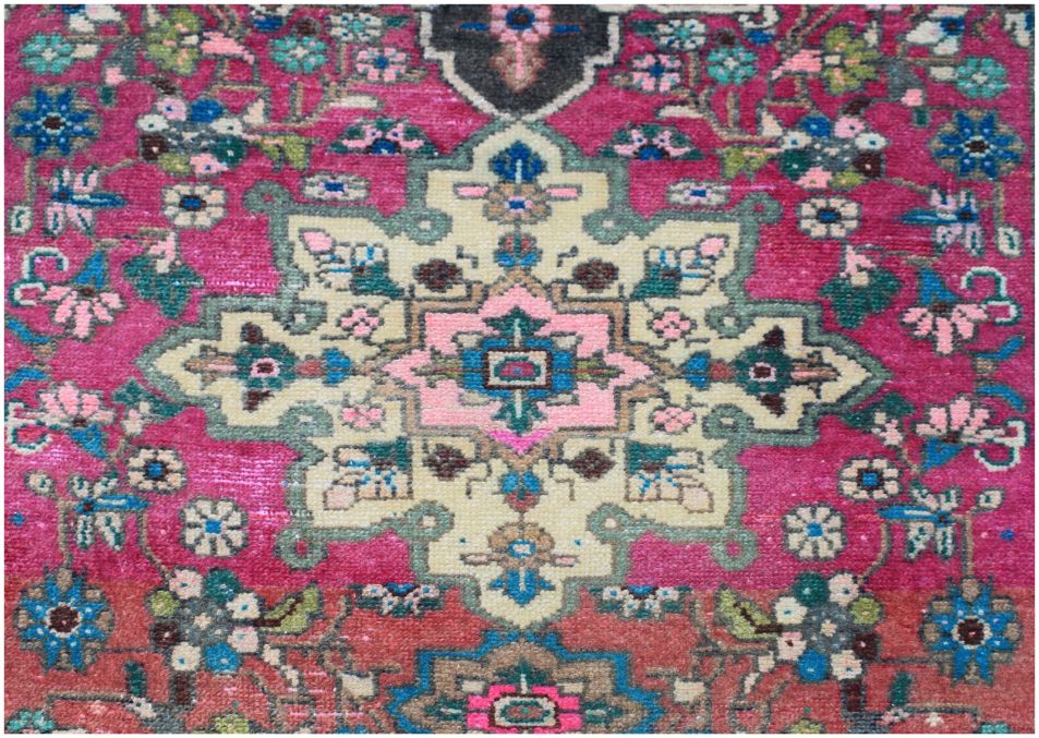 A vintage Persian runner featuring a central floral medallion on a vibrant magenta background.