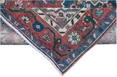 A corner view of a vintage Persian runner featuring intricate floral patterns in red and blue.