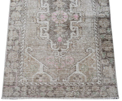 A handwoven vintage Persian runner featuring a faded geometric pattern in beige and soft pink.