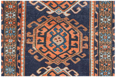 A vintage handwoven Persian runner featuring geometric orange medallions on a dark blue background.