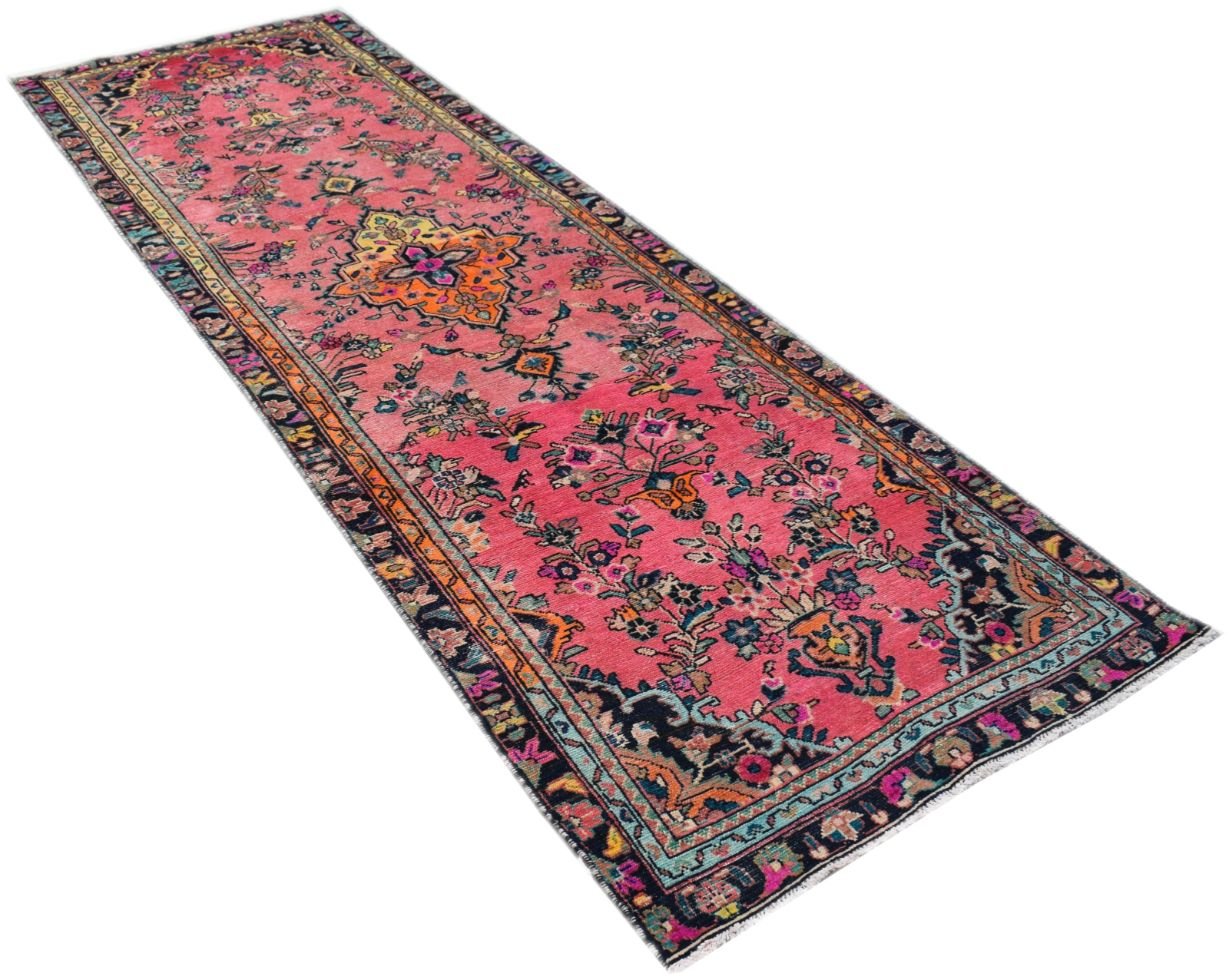 A vintage Persian runner rug featuring a vibrant pink field with intricate floral patterns.