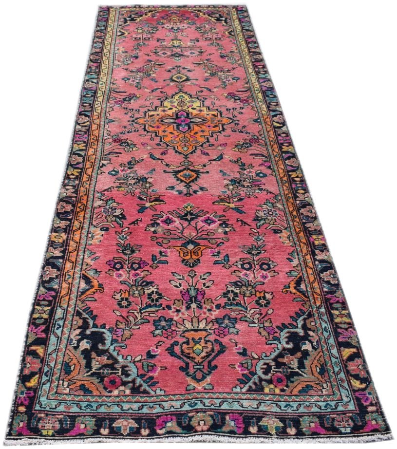A handmade vintage Persian runner rug featuring a pink field with intricate floral and tribal motifs.