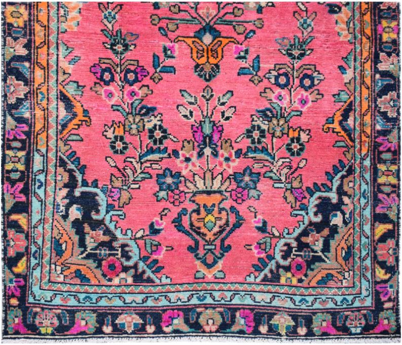 A handmade vintage Persian runner featuring a vibrant pink field with floral and urn motifs.