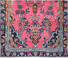 A handmade vintage Persian runner featuring a vibrant pink field with floral and urn motifs.