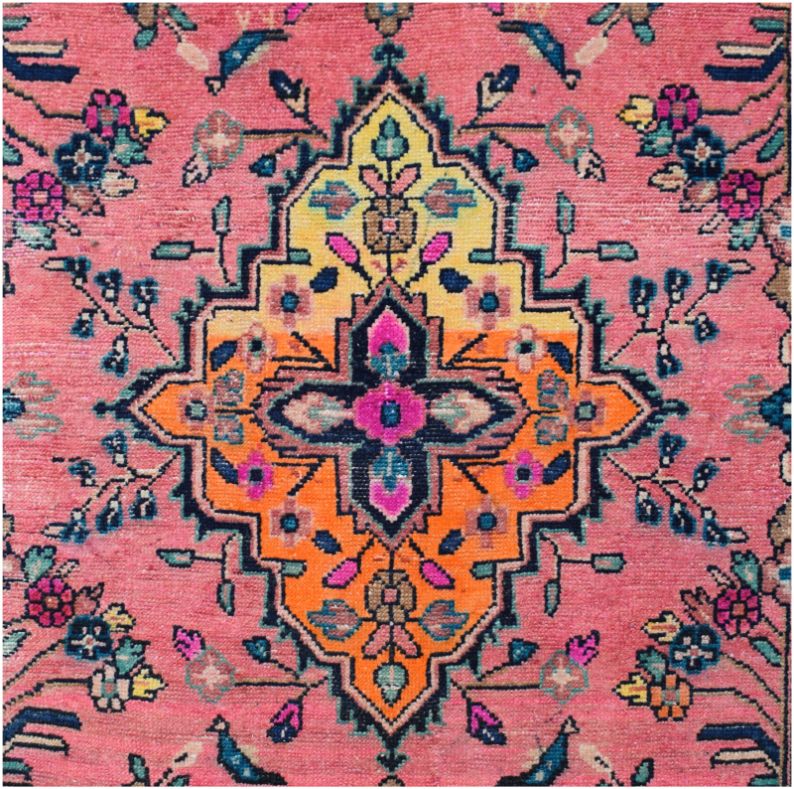 A vintage Persian runner featuring a central geometric medallion in yellow and orange on a pink field.