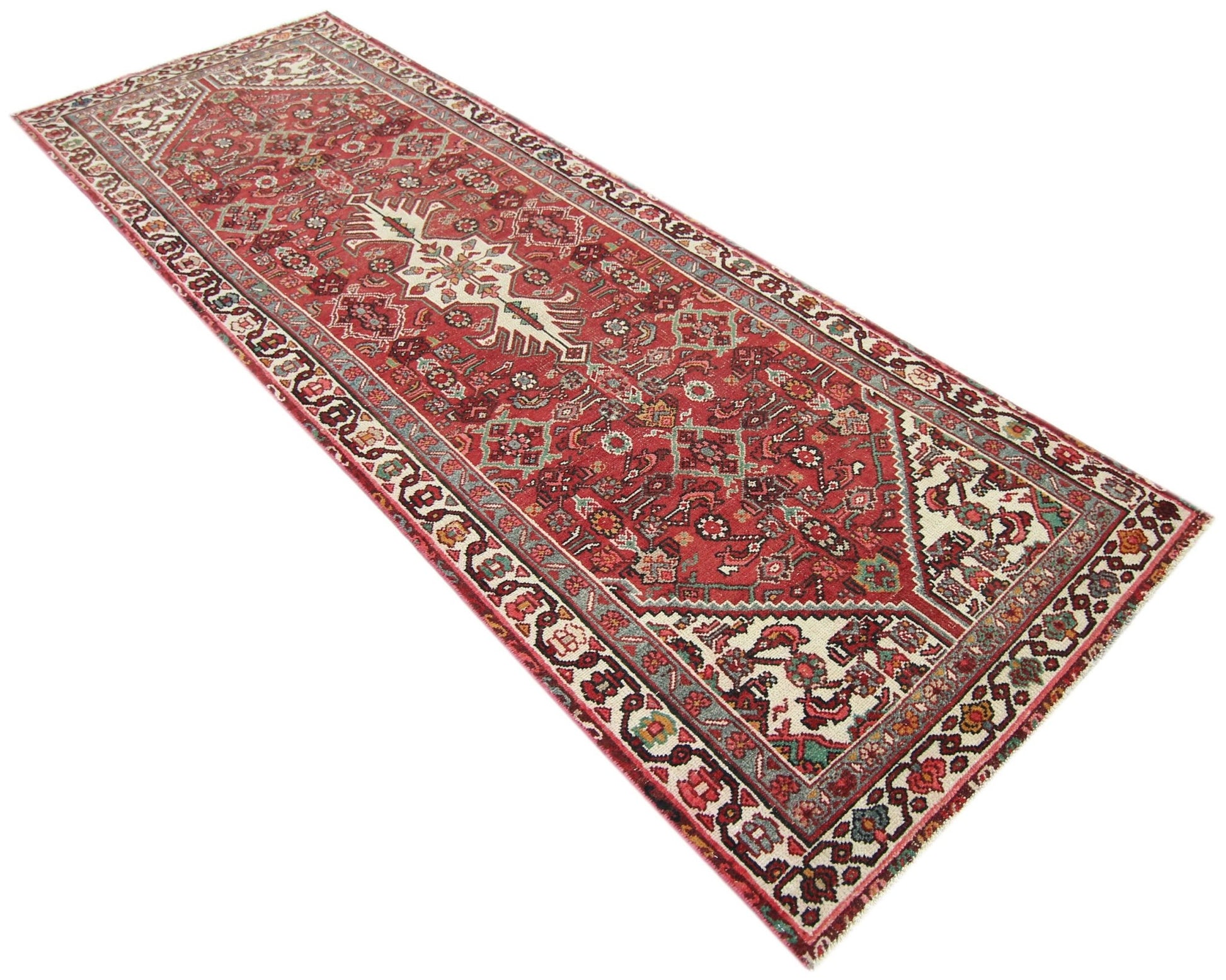 A handmade vintage Persian runner rug featuring intricate floral patterns in red and cream tones.