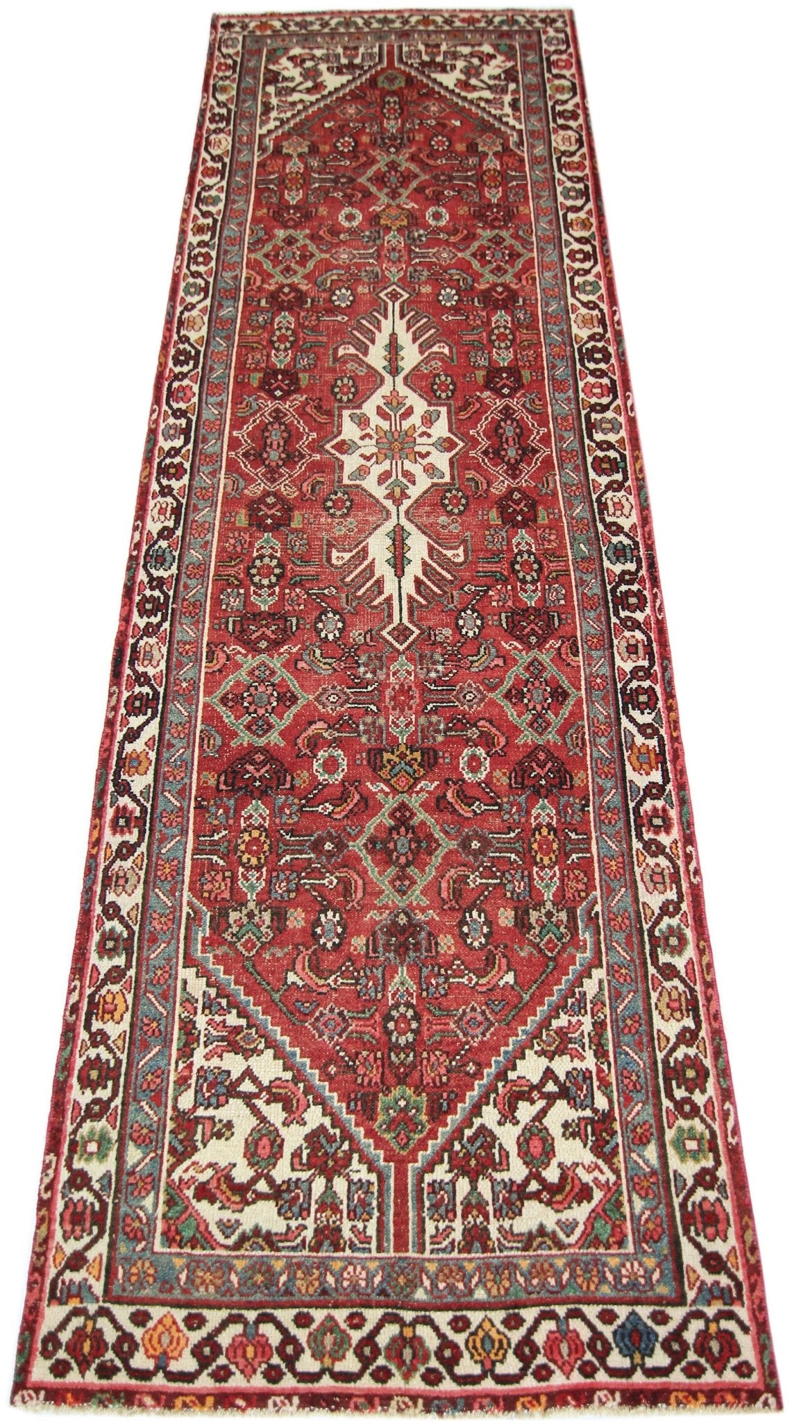 A vintage handmade Persian runner featuring a red field with intricate geometric floral patterns.