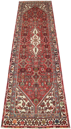 A vintage handmade Persian runner featuring a red field with intricate geometric floral patterns.