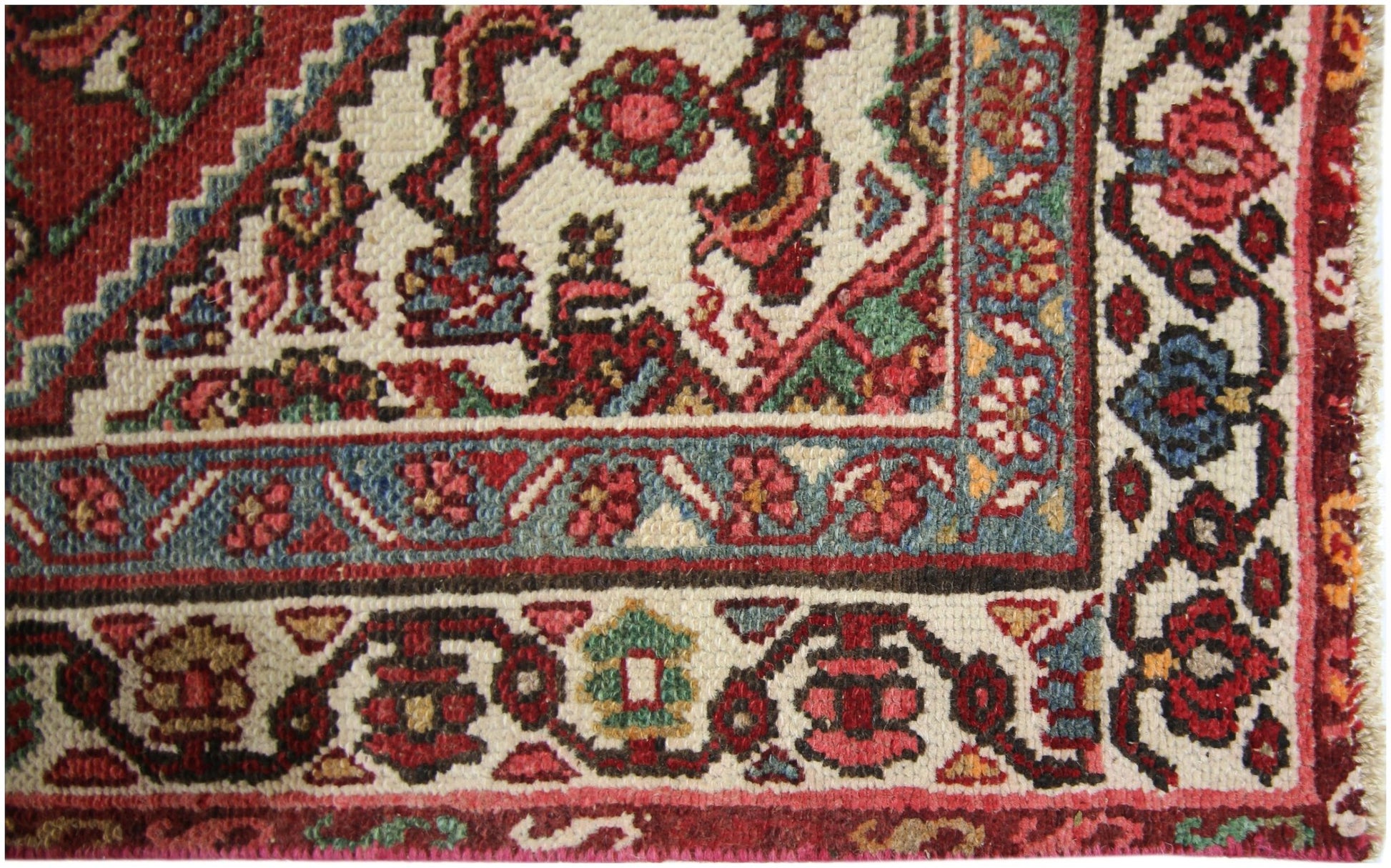 A close-up of a vintage Persian runner featuring intricate floral patterns in red, blue, and cream.