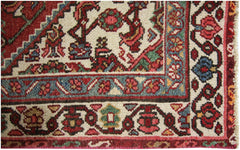 A close-up of a vintage Persian runner featuring intricate floral patterns in red, blue, and cream.