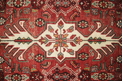 A vintage Persian runner featuring a geometric floral medallion pattern in red, cream, and green.